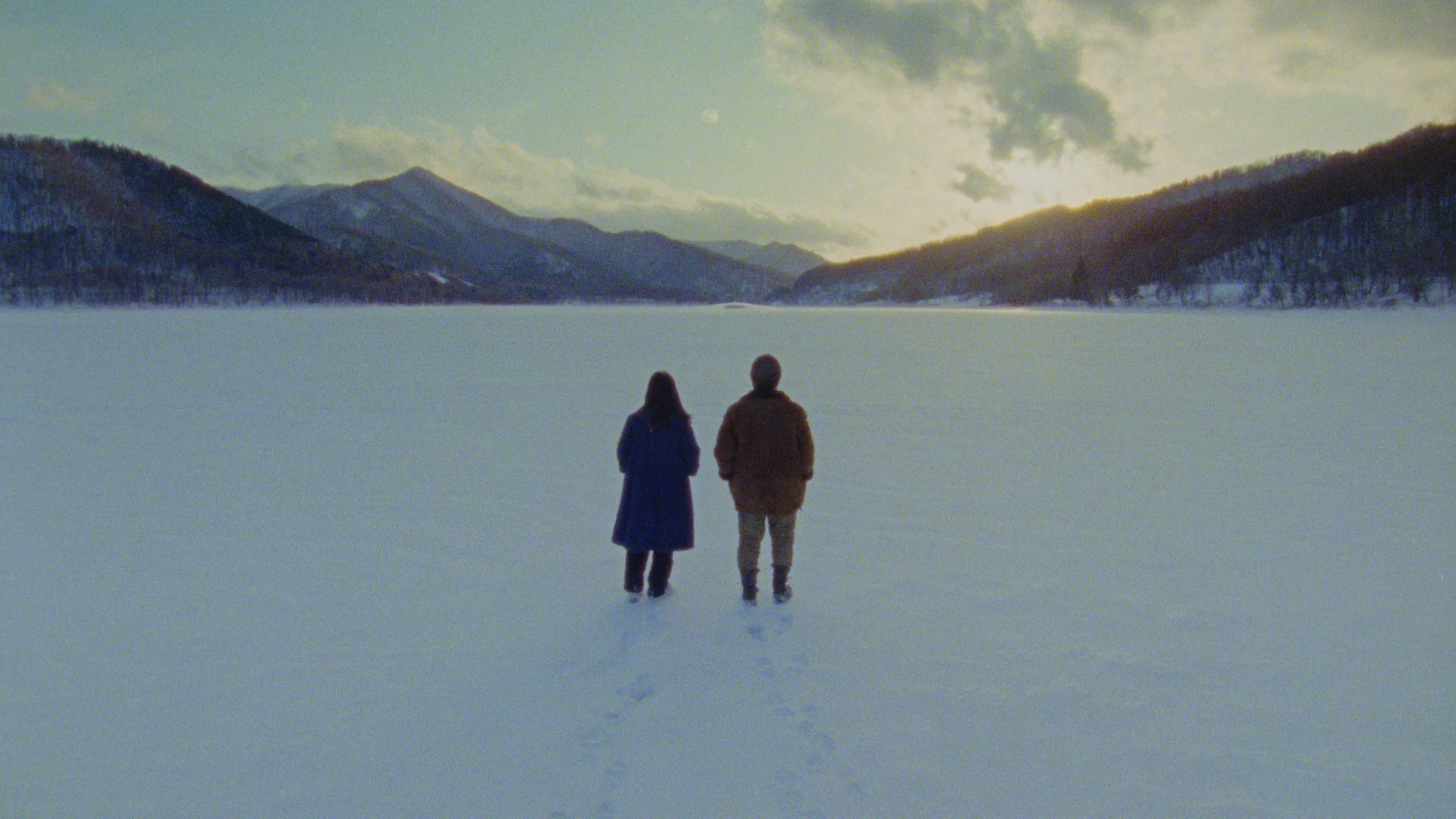 Two figures walking across a frozen lake