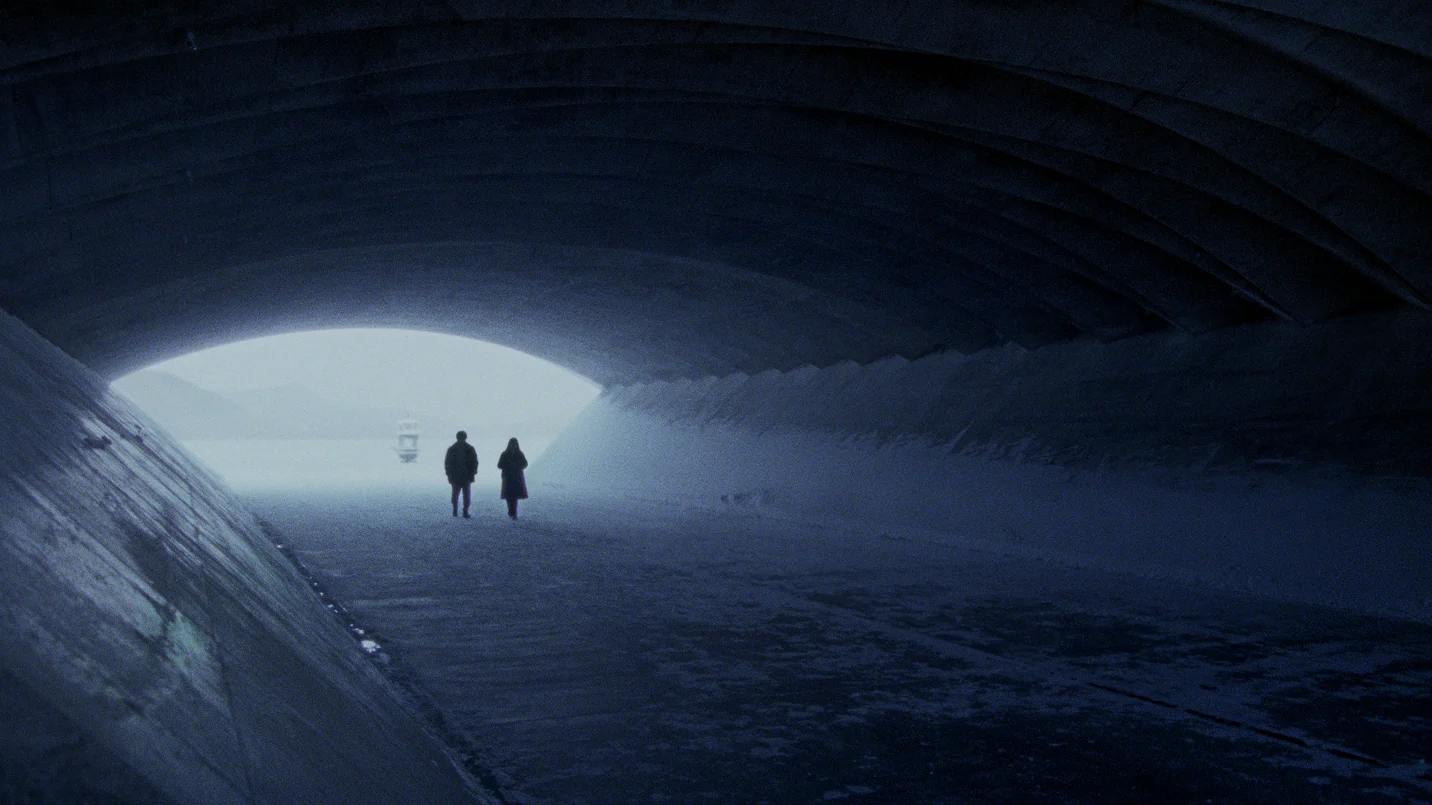 Two figures standing inside a vast snowy tunnel