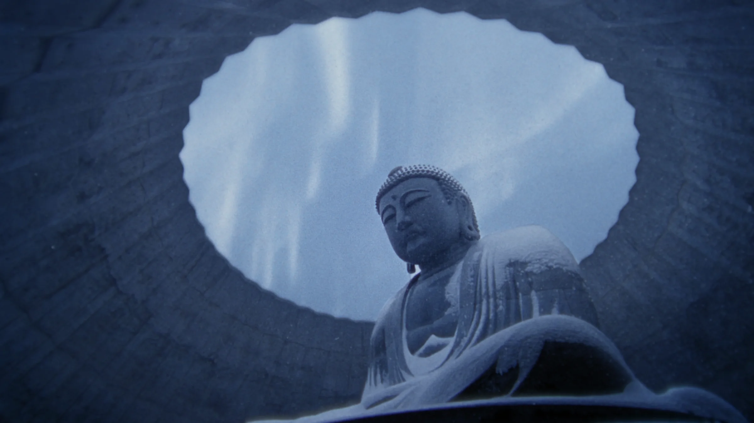 A Buddha statue seen through a circular opening